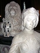 Im Hintergrund eine von vorne gesehene Statue eines liegenden Löwen, der zwischen seinen Pfoten ein von einer Krone bekröntes Wappen trägt.