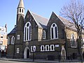 The former St Barnabas Church, Kentish Town Road, Camden in London, 1884–85 by Ewan Christian, now the Greek Orthodox Cathedral of St Andrew, showing the west front with north apse and turret[156]