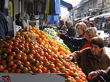 Shoppers inspect the quality of fresh produce at a market in Jerusalem. Mahane Yehuda shoppers.jpg