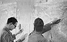 National Guardsmen with a map of San Francisco, partially illustrating the Fillmore curfew area, in the emergency operation center. National Guard area deployment section.jpg