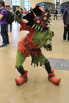Personnage portant un costume d'un personnage fictif, de couleur verte et rouge, ainsi qu'un masque.