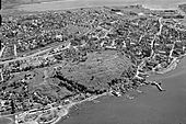 Domkirken ligger sør for Slottsfjellet, landemerket i byen, til høyre i bildet. Flyfoto fra 1957. Foto: Widerøe/Vestfoldmuseene