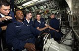 US Navy 040815-N-6811L-017 USS Portsmouth (SSN 707) Diving Officer of the Watch, Senior Chief Store Keeper Albert Holguin, gives instruction to Fireman Joel Johnson on proper operating procedures for the Helmsman.jpg