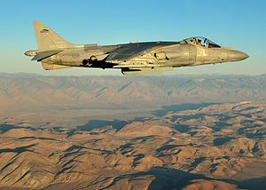 Side view of fighter jet flying above mountain range