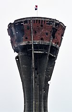 The water tower in Vukovar, 2005. Heavily damaged in the battle, it has been preserved as a symbol of the town's suffering. Vukovar water tank.jpg