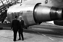 Technical director Roger Beteille (from behind) discussing with general manager Henri Ziegler beside the CF6 turbofan, which powered the A300 first flight 28.10.72 1er Vol d'Airbus (1972) - 53Fi1992 (cropped).jpg