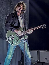 Photographie d'un chanteur jouant de la guitare lors d'un concert