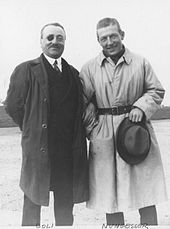 Photo en noir et blanc de deux hommes représentant Nungesser et Coli, en imperméables, debout.