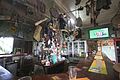 The Cracow Hotel pub's bar with rugby on the TV. Note the car door hanging on the wall in the picture's upper left corner and Fred Brophy's drum on top of the fridges, next to the crocodile's scull.