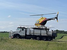 Crop spraying helicopter on a landing pad atop its refueling truck