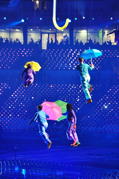 Performers holding umbrellas fly around the stadium.