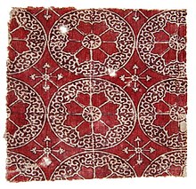 Textile fragment, 24 cm x 21 cm, made circa 1545 - 1645 AD. Produced in India for export, found in Fustat, Egypt. The brown colored pattern is formed by the use of a mordant applied to the ground cloth with a single stamp. The red dye was then painted on. The outline of the square block, forming four quarter circles with the star shape in the middle, is faintly visible. Fustat Indian.jpg