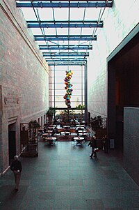 From the balcony at the east end of the atrium, one can see another Chihuly work, Glowing Gemstone Polyvitro Chandelier, hanging above the cafe. Joslyn Atrium South.jpg