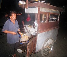 A street vendor cooking nasi goreng in his cart. The travelling night hawkers often frequenting Jakarta residential area. Nasi Goreng Travelling Vendor in Jakarta.JPG