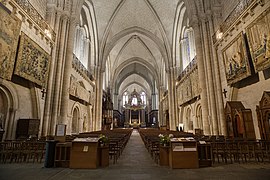 Bir katedral nefinin ve asılı duvar halılarının fotoğrafı.