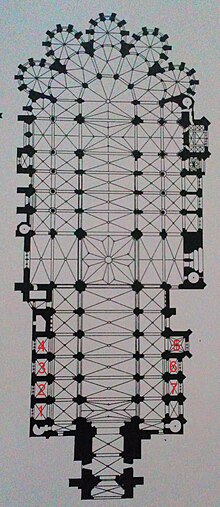 Plan représentant un long bâtiment en forme de croix de Lorraine avec, en bas à gauche et à droite de l'image, les chiffres 1, 2, 3, 4, 5, 6 et 7 écrits en rouge sur des pièces latérales.