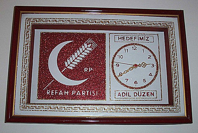 A clock displaying the emblem of the Welfare Party. The party slogan translates as "Justice is our goal."