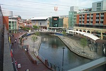 Stretch of canal with large modern buildings and concrete walkways on either side.