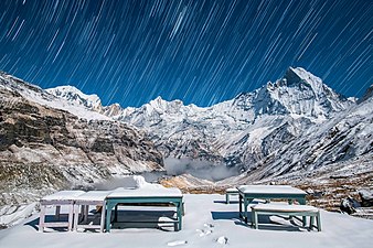 The view of mount Machhapuchre from Annapurna base camp with fresh snow under moonlight and the trails of stars over it.