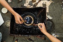 صنعتگران باتیک در یک کارگاه در دهکدهٔ گولورجو، نزدیک یوگیاکارتا، موم مایع داغ را درون مخزن قلم کلاقه می‌ریزند