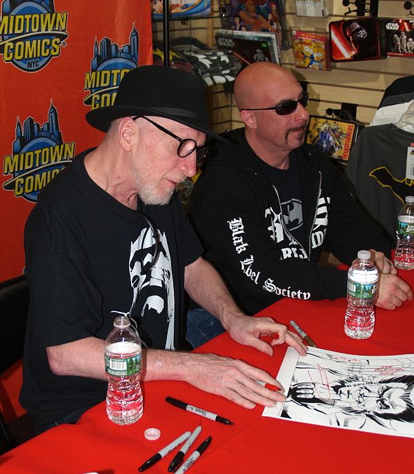 Frank Miller (left) signing a print of his artwork for the cover of Vol. 1 #1 at an appearance at Midtown Comics. Beside him is artist Greg Capullo.