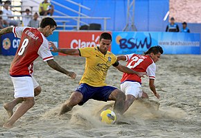 A scene from the 2015 CONMEBOL Beach Soccer Championship match between Brazil and Paraguay with the BSWW logo on hoarding visible in the background FUTBOL PLAYA (17098874369).jpg