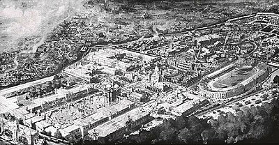 Zwart-wit luchtfoto van een sportterrein, rechts is een stadion zichtbaar