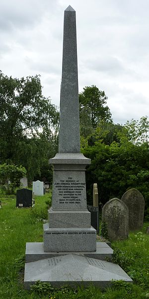 A polished, grey, obelisk-like funerary monument surmounting a grave
