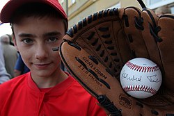 A child holds a baseball signed by Donald Tusk in a baseball glove Kutno jest stolica polskiego baseball'u (6169383031).jpg