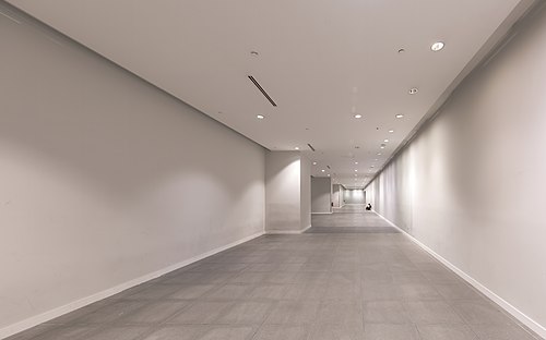 Long corridor with someone sitting on the floor in the distance at Marina Bay MRT Station Singapore