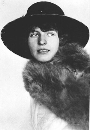 תמונה בשחור לבן. מריאנה גולץ במרכז התמונה, פניה לעבר הצופה, אך עיניה פונות לימין התמונה. היא לובשת מעיל פרווה וכובע רחב שוליים.