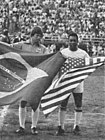 Pelé in his debut with the Cosmos, holding an US flag while the Dallas Tornado player holds a Brazilian flag. (15 June 1975)