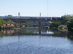 Tren diésel del Ferrocarril General Roca sobre el Riachuelo. Al fondo se encuentra el Puente Bosch.