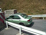 石榑峠コンクリートブロック（滋賀県側）を通行している車の様子。コンクリートブロックの側面には水平に付けられた筋状の傷が無数に見て取れる。