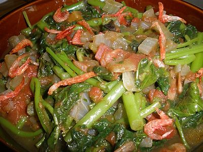 Closeup of stewed green leaves, tomato and tiny shrimp