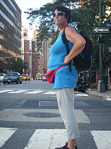 A woman wearing a fanny pack stands with arms akimbo Red Fanny Pack.jpg