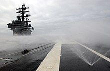 The counter-measure wash-down system of the USS Ronald Reagan (CVN-76), part of the vessel's CBRN defenses US Navy 050615-N-8148A-063 The Nimitz-class aircraft carrier USS Ronald Reagan (CVN 76) activates her countermeasures wash down system as part of a series of test and evaluations to certify the vessel in the event of a chemical.jpg