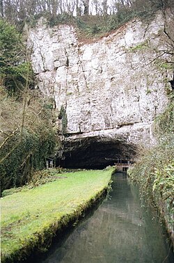 Een klif met een grot aan de basis waaruit de rivier de Ax . stroomt