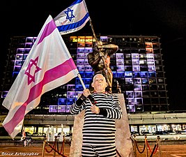 פסל גיבור ישראל בחזית בית עיריית תל אביב-יפו ולפניו מפגין מחופש לנתניהו