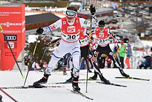Bir kros kayakçısı, diğer iki yarışmacının önünde tam tırmanışa geçti.