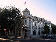 Gambar dari depan sudut dari Bank of San Mateo County gedung dengan bendera berkibar di angin di atas.