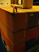 Dockworker installs a twistlock on a high stack of containers