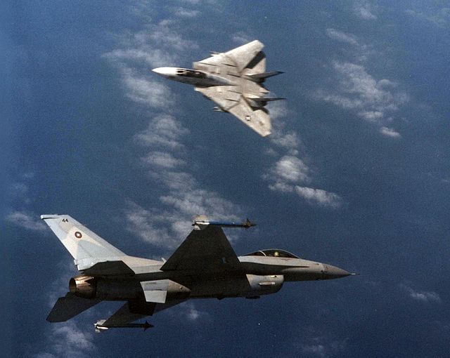 An F-16 Fighting Falcon and an F-14 Tomcat engaged in a mock dogfight as part of U.S. Navy TOPGUN training