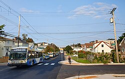 City buses, automobiles coming up a street and a cyclist going down