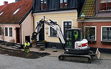 A Bobcat excavator is digging for the laying of a broadband cable in central Ystad. Gravmaskin - Ystad-2021.jpg