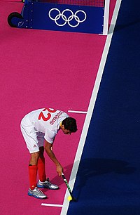 Simon Gougnard prepares to take a penalty corner from the 10 m mark. The 5 m line above demarcates the closest position a defender may stand. Hockey short corner markings.jpg