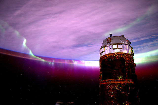 A view of the docked Kounotori 5 spacecraft from the Cupola, with Aurora Australis in the background.