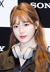 IU with a pair of white headphones around her neck looking forwards