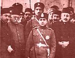 Reza Khan standing behind the man whom he would overthrow, Ahmad Shah Reza Kahn behind Ahmad Shah.jpg