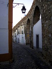 Traditional homes built between the arches of the Água de Prata Aqueduct in Évora, Portugal
